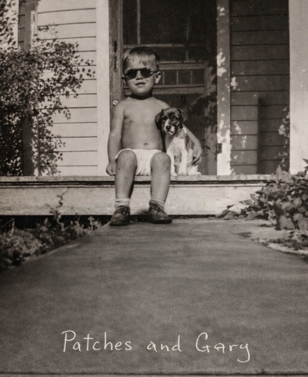 Young Gary sitting on a porch with Patches the dog